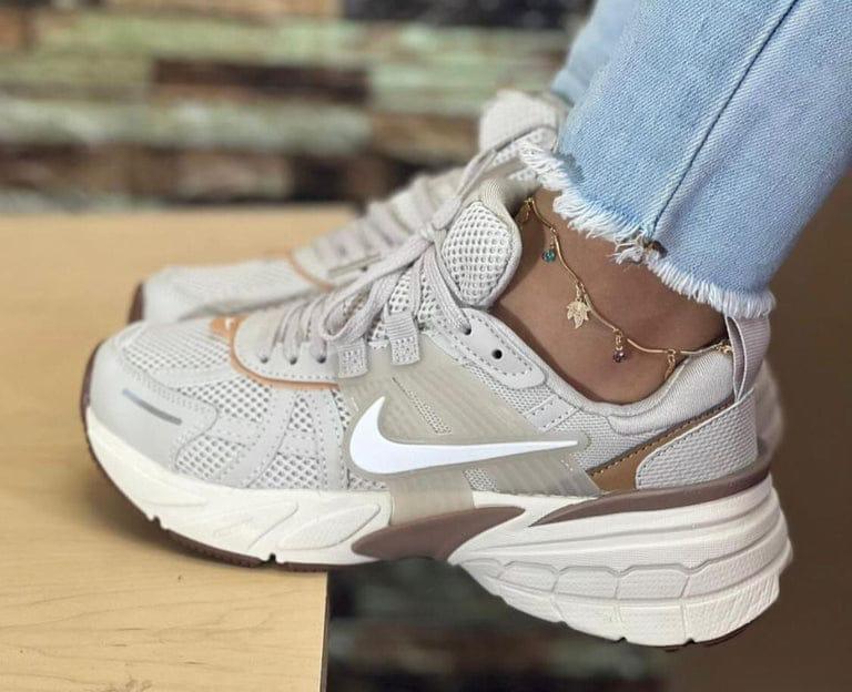Tenis Nike deportivos blancos con detalles beige y suela gruesa.