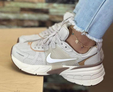 Tenis Nike deportivos blancos con detalles beige y suela gruesa.